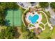 Overhead view of a sparkling community pool, tennis courts, and verdant landscaping at 23814 Sardinia Dr, Sorrento, FL 32776