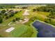 Scenic aerial shot of a golf course with sand traps, water feature, and lush greenery at 23814 Sardinia Dr, Sorrento, FL 32776