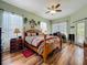 Bedroom with wood floors, ceiling fan, and a desk perfect for work or study and white curtains at 25545 Laurel Valley Rd, Leesburg, FL 34748