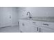 Laundry room featuring white cabinets, granite countertop and stainless steel faucet, with gray tile floors at 2581 Se 75Th Blvd, Bushnell, FL 33513