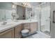 Bright bathroom with double vanity, framed mirrors, soft lighting, and a glass-enclosed shower at 25818 Belle Alliance, Leesburg, FL 34748