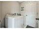 Laundry room featuring a white washer and dryer, and a nearby door at 25818 Belle Alliance, Leesburg, FL 34748