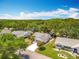 A high-angle aerial view of the house with a blue sky and wooded area background at 26823 Forest Hills St, Leesburg, FL 34788