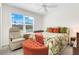 Cozy bedroom with a brightly patterned bed, recliner, ottoman, ceiling fan, and a window view at 2775 Navy Hill Cir, The Villages, FL 32163
