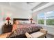 Spacious main bedroom featuring a decorative tray ceiling, large window, and elegant furnishings at 2775 Navy Hill Cir, The Villages, FL 32163
