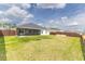Backyard featuring a large lawn, dark wood fence, a screened porch, and two wooden planter boxes at 3273 Dzuro Dr, Oxford, FL 34484