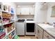 Organized laundry room with a large sink, upper cabinets, shelving, and modern white washer and dryer at 3273 Dzuro Dr, Oxford, FL 34484