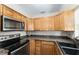 Efficient kitchen layout with sleek black appliances, granite countertops, and wood cabinetry at 36337 Terra Ct, Grand Island, FL 32735
