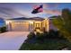 Charming single-story home boasting a two-car garage, well-manicured lawn, and an American flag, illuminated by soft evening light at 3641 Arlington Ridge Blvd, Leesburg, FL 34748