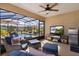Relaxing screened patio features comfortable seating, TV, ceiling fan, and overlooks sparkling pool for the ultimate outdoor experience at 3641 Arlington Ridge Blvd, Leesburg, FL 34748