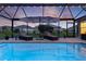 Inviting screened-in pool featuring two lounge chairs with umbrellas and exterior lights for evening enjoyment at 3641 Arlington Ridge Blvd, Leesburg, FL 34748