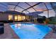 Inviting screened-in pool with ambient lighting, patio furniture, and umbrella, perfect for relaxing evenings and outdoor entertainment at 3641 Arlington Ridge Blvd, Leesburg, FL 34748