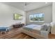 Modern bedroom with wood floors, TV, blue accents, and a cozy bed near a window overlooking the trees at 4131 Sunset Preserve Blvd, Orlando, FL 32820