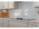 White kitchen with stainless appliances and herringbone backsplash, and smooth cooktop at 4131 Sunset Preserve Blvd, Orlando, FL 32820