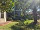 View of the backyard with a screened-in lanai, lush green grass, and tropical landscaping with palm trees at 5008 Sawgrass Lake Cir, Leesburg, FL 34748