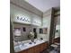 Bright bathroom with double sinks, vanity lighting, and decorative accents at 5008 Sawgrass Lake Cir, Leesburg, FL 34748
