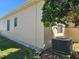 Beige exterior home featuring a lush green lawn, air conditioning system, and window at 5008 Sawgrass Lake Cir, Leesburg, FL 34748