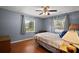 Comfortable bedroom with hardwood floors, ceiling fan, two bright windows, and light-colored walls at 5331 Magnolia Ridge Rd, Fruitland Park, FL 34731