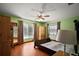 Cozy bedroom featuring a ceiling fan, two large windows, hardwood floors, and an armoire for ample storage at 5331 Magnolia Ridge Rd, Fruitland Park, FL 34731