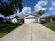 Charming single-story home with a long driveway and well-manicured lawn with palms in the yard at 664 San Pedro Dr, The Villages, FL 32159