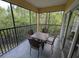 View of a screened in porch with table and seating surrounded by mature trees and lush greenery at 8801 Worldquest Blvd # 4203, Orlando, FL 32821