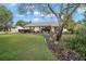 Well-manicured front yard with lush green lawn, colorful flower beds, and mature trees creating inviting curb appeal at 97 Hillside Dr, Eustis, FL 32726