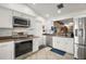 Well-equipped kitchen with white cabinets, stainless steel appliances, and a view into the dining area at 97 Hillside Dr, Eustis, FL 32726