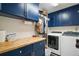 Functional laundry room with modern washer and dryer, navy blue cabinetry, and folding space for added convenience at 97 Hillside Dr, Eustis, FL 32726