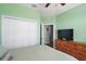 Bright bedroom featuring a closet, dresser with TV, and an open doorway at 971 Caribou Way, The Villages, FL 32162