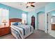 Comfortable bedroom features blue walls, a ceiling fan, soft carpet and a doorway to the en suite bathroom at 971 Caribou Way, The Villages, FL 32162