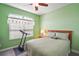 Comfortable bedroom with a queen-sized bed, floral curtains, and exercise equipment at 971 Caribou Way, The Villages, FL 32162