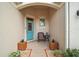 Inviting front porch with a chair, table, and decorative plants near a vibrant front door at 971 Caribou Way, The Villages, FL 32162