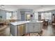 Open kitchen featuring a central island with a stainless steel dishwasher, sink, and views into the living and dining areas at 971 Caribou Way, The Villages, FL 32162