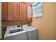 Well-equipped laundry room with a washer, dryer, and storage cabinets above appliances at 971 Caribou Way, The Villages, FL 32162