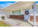 A decorative wreath and potted plants adorn the cozy front porch with brick accents at 9773 Se 179Th Pl, Summerfield, FL 34491