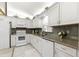 Well-lit kitchen showcases white cabinets, granite countertops, stainless steel appliances and tile flooring at 9773 Se 179Th Pl, Summerfield, FL 34491