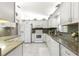 Well-lit kitchen features white cabinets, granite countertops, tile flooring and stainless steel appliances at 9773 Se 179Th Pl, Summerfield, FL 34491