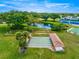 Aerial view featuring shuffleboard courts with adjacent pond, greenery, and tennis and bocce ball courts at 9773 Se 179Th Pl, Summerfield, FL 34491