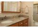 Bathroom featuring double sinks, granite countertops, and a tiled shower enclosure at 9948 Se 175Th Pl, Summerfield, FL 34491