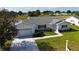 Aerial view of home with green lawn, landscaping, lake view, and charming curb appeal at 9948 Se 175Th Pl, Summerfield, FL 34491