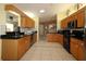Open kitchen with wood cabinets, black appliances, and tiled flooring with a connecting dining area at 9948 Se 175Th Pl, Summerfield, FL 34491