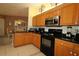 Kitchen with black appliances, wood cabinets, and granite countertops, open to the dining area at 9948 Se 175Th Pl, Summerfield, FL 34491