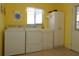 Yellow laundry room with washer, dryer, utility sink, cabinet, and tile floors at 9948 Se 175Th Pl, Summerfield, FL 34491