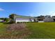 View of back exterior with trimmed bushes and an enclosed lanai, showcasing the home's serene outdoor space at 9948 Se 175Th Pl, Summerfield, FL 34491