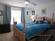 A bright bedroom with a wooden bed frame, blue bedding, and a window with curtains at 1010 Chelsea Dr, Davenport, FL 33897