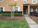 Charming townhome featuring manicured landscaping, healthy trees, and a welcoming entrance at 1010 Chelsea Dr, Davenport, FL 33897