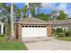 Attached two-car garage with a white door and brick exterior; front lawn and landscaping at 1022 Saint Ives Ct, Mount Dora, FL 32757