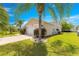 Angle view of home's exterior featuring a well-manicured lawn, mature palms and a two-car garage at 1089 Nash Loop, The Villages, FL 32162