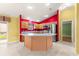 Kitchen with stainless steel appliances, red accent wall and central island at 1089 Nash Loop, The Villages, FL 32162
