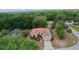 Aerial view of a home with a terracotta roof surrounded by mature trees, a driveway, and partial view of a neighborhood street at 11497 Sw 82Nd Court Rd, Ocala, FL 34481